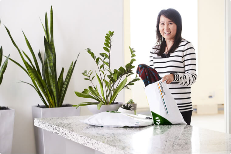 Woman standing in the kitchen opening a MyTeamGE satchel